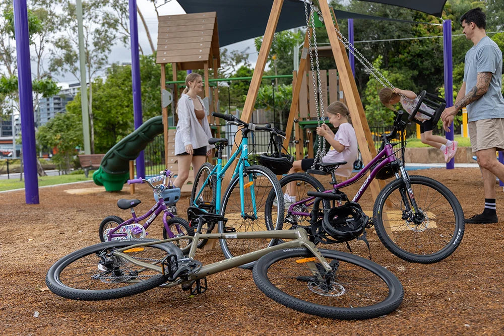 The best mother's day gift ideas at Bicycle Centre. Family at the playground after a bike ride with their bicycles at the front.