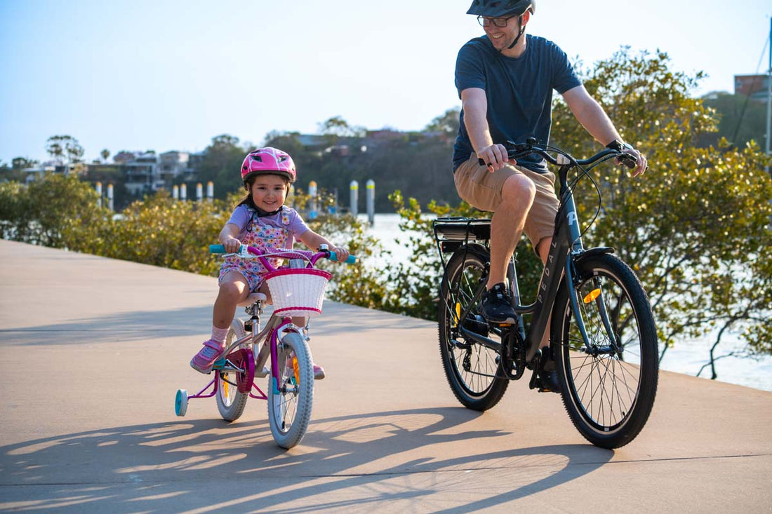 Pedal Bikes available at Bicycle Centre. Daughter and Dad riding along the river smiling and having the best time together outdoors on their bicycles. Bicycle Centre