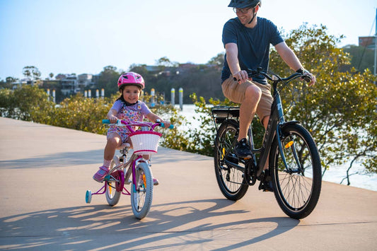 Pedal Bikes available at Bicycle Centre. Daughter and Dad riding along the river smiling and having the best time together outdoors on their bicycles. Bicycle Centre